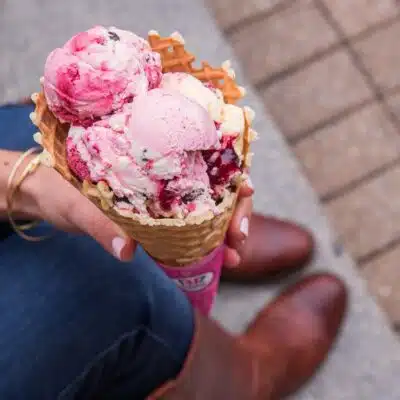 Woman holding waffle cone with strawberry ice cream