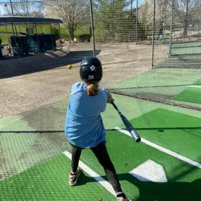 Child swinging bat inside batting cages at Adventure Falls
