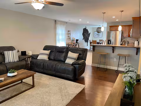 Living room of short-term rental, featuring a three-seat couch and open-concept floorplan between the living room, dining room, and kitchen