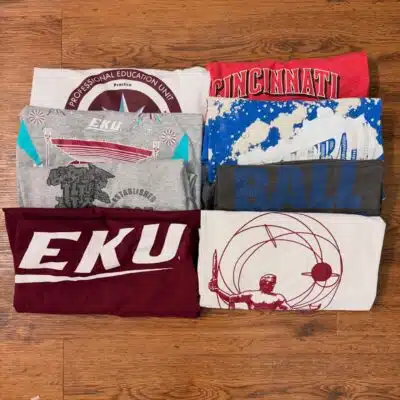 Folded pile of EKU shirts available at Retro Rags Vintage