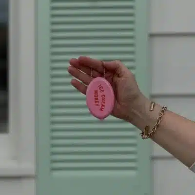 Holding pink coin purse reading 'ice cream money' in front of mint green shutter