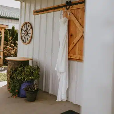 Wedding dress hanging on wooden barn door at Chenault Vineyards