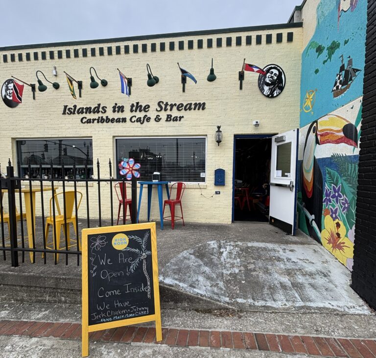 Exterior of Islands in the Stream featuring the mural of a toucan and outdoor seating