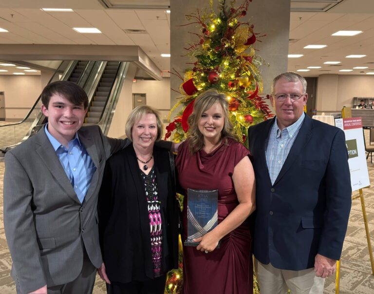 Lori Murphy-Tatum holding award while standing with her family