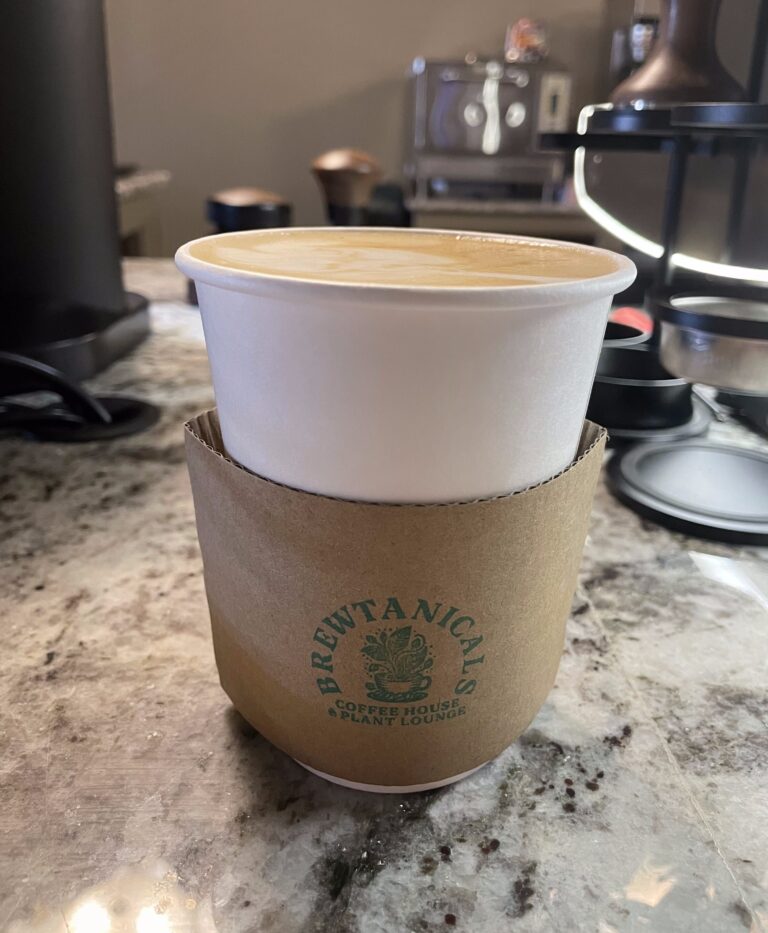 Brewtanicals latte featuring logo on sleeve
