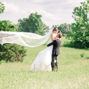 Groom holding bride with veil in wind at SMK Agricultural Venue