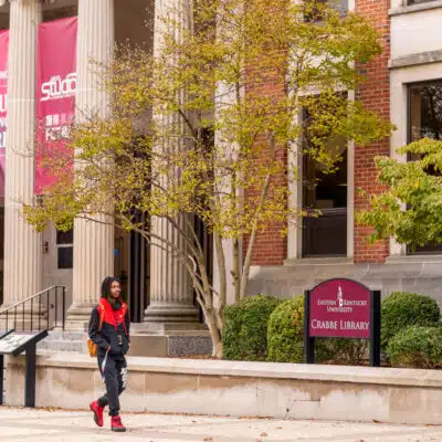 Student walking in front of the library on EKU's campus
