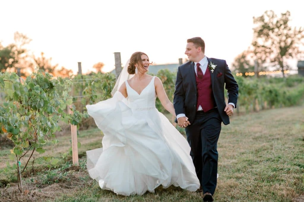 Bride and groom scampering through the vineyard