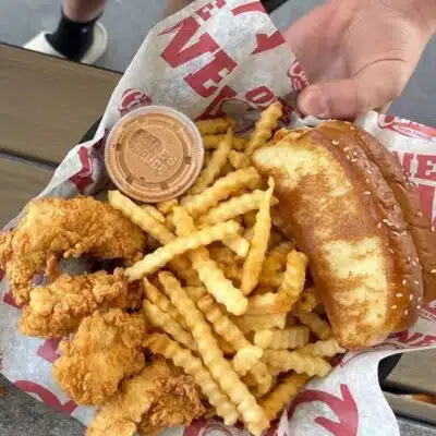 Raising Cane's combo with hand reaching in for slice of Texas Toast